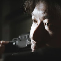 暗闇の中でビデオカメラを構える職人気質のカメラマンの写真