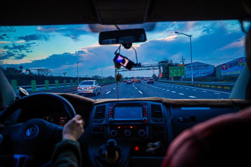 高速道路を走る運転席からの景色と運転者の手元