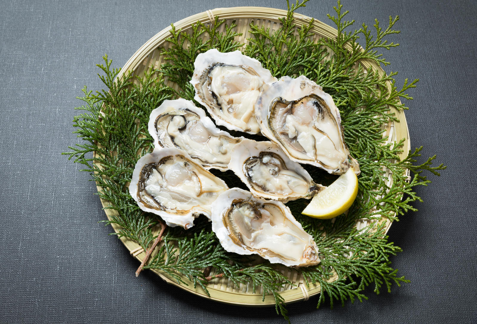 竹ざるに盛られた殻付き恵比須牡蠣とレモン