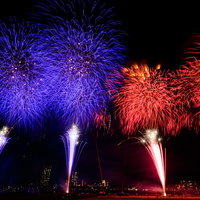 青と赤に別れて打ち上げるスターマインの花火の写真