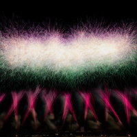 目の前に広がるスターマイン花火の光跡と火の粉の写真