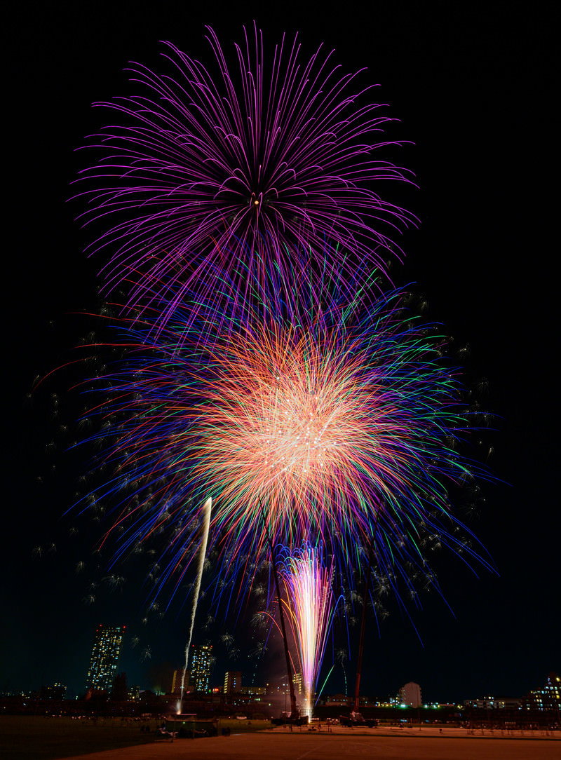 夜空に紫やオレンジ、青の花火が開いている様子