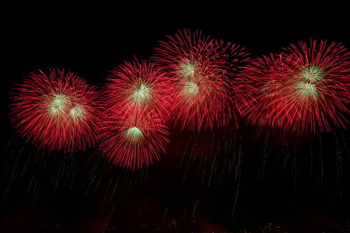 夜空に流れる赤い打上花火とスターマインの爆発