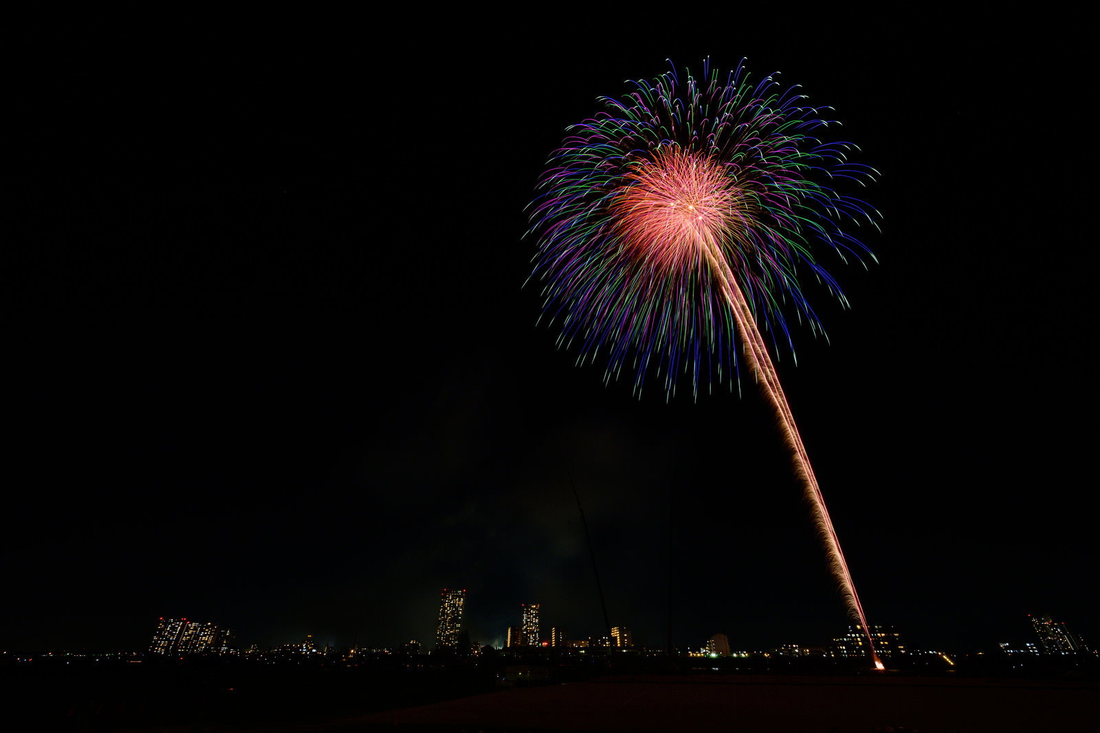 暗い夜空に色とりどりの花火が大きく開いている様子