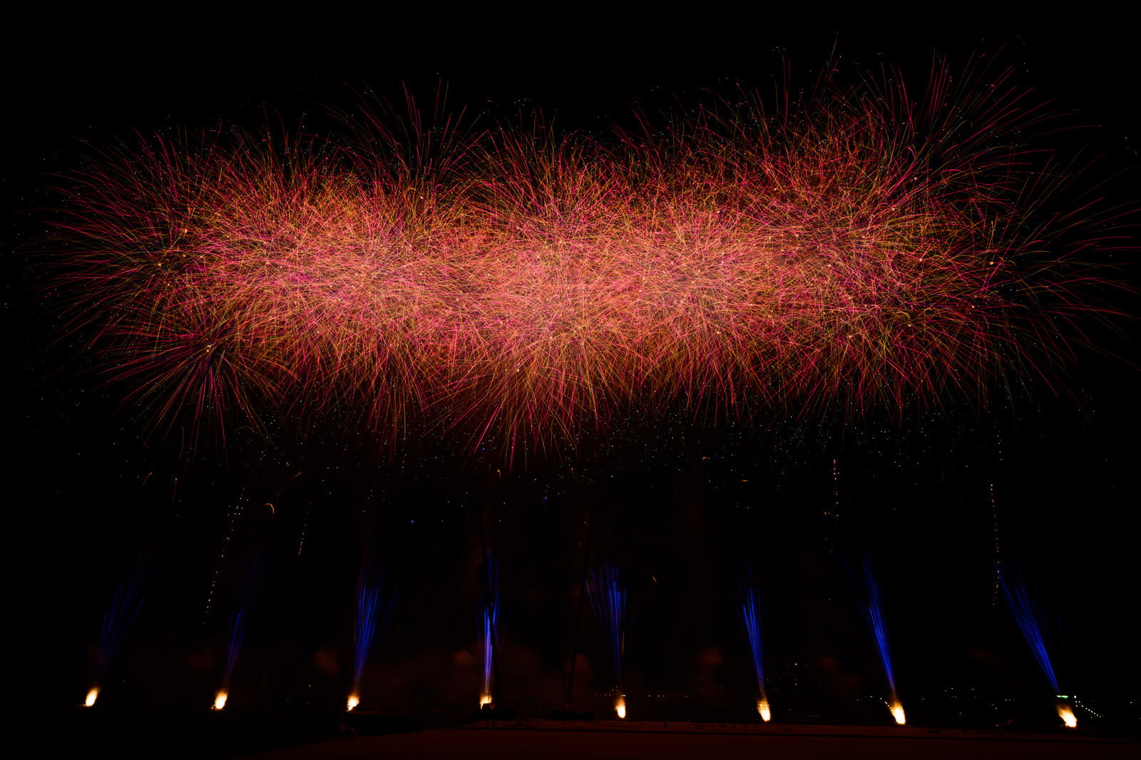 夜空に赤い光跡を放射状に広げる打ち上げ花火