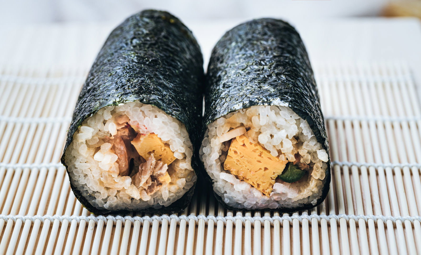 竹すだれの上に置かれたコンビニの恵方巻2本