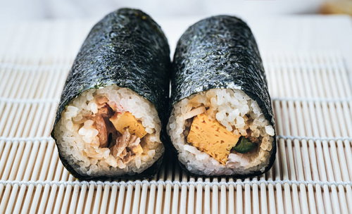 コンビニで買った恵方巻、竹のすだれの上に2本並べた食卓