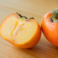 秋の味覚、カットした柿と丸ごとの柿のの写真