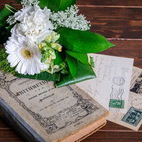 古い洋書と葉書の上に置かれた白いブーケの写真