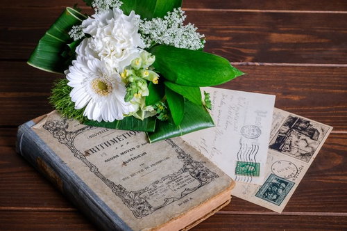 古い洋書と葉書の上に置かれた白いブーケ