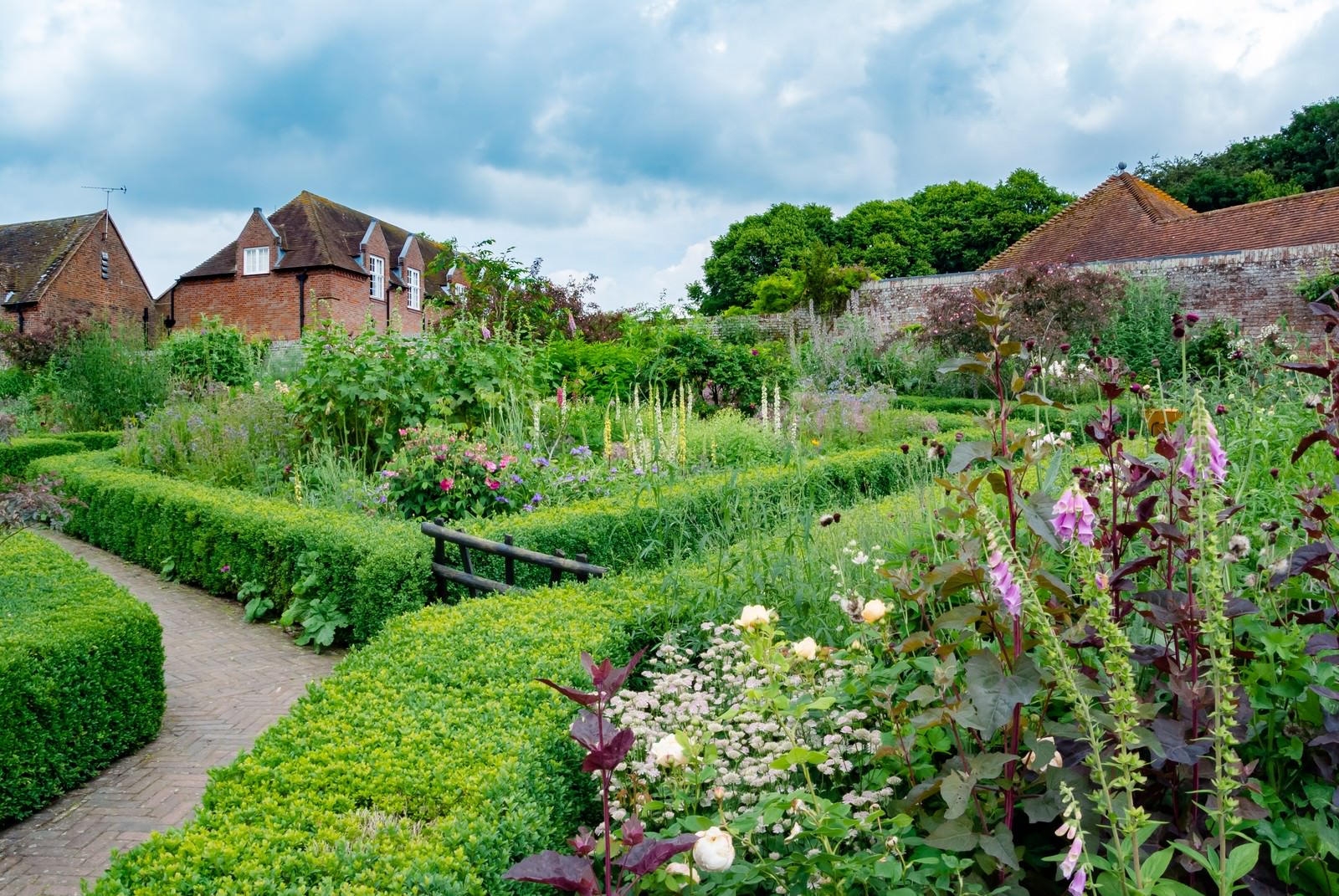 レンガ造りの邸宅に隣接する花壇と生垣の庭園