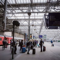 エディンバラ駅のプラットフォームで荷物を持つ乗客たちの写真