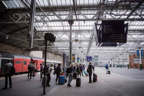 エディンバラ駅のプラットフォームで荷物を持つ乗客たち
