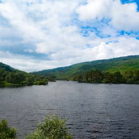 湖畔の緑の山々に囲まれた湖、青空と白い雲が映える景勝地の写真