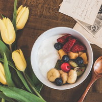 机の上に並んだヨーグルトフルーツ添えとスプーンの写真