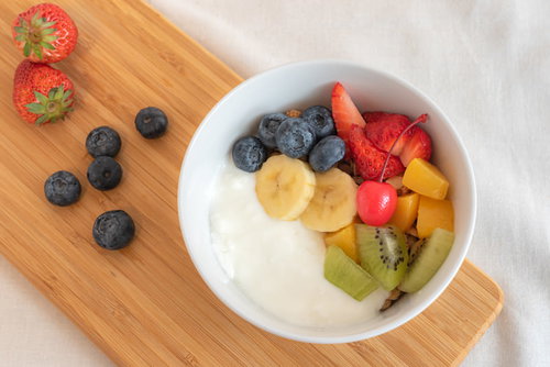 木製まな板に置いたヨーグルトフルーツ添え