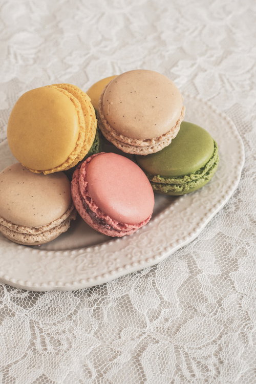 三時のおやつに色とりどりのマカロン、白いお皿に並ぶカラフルなスイーツ