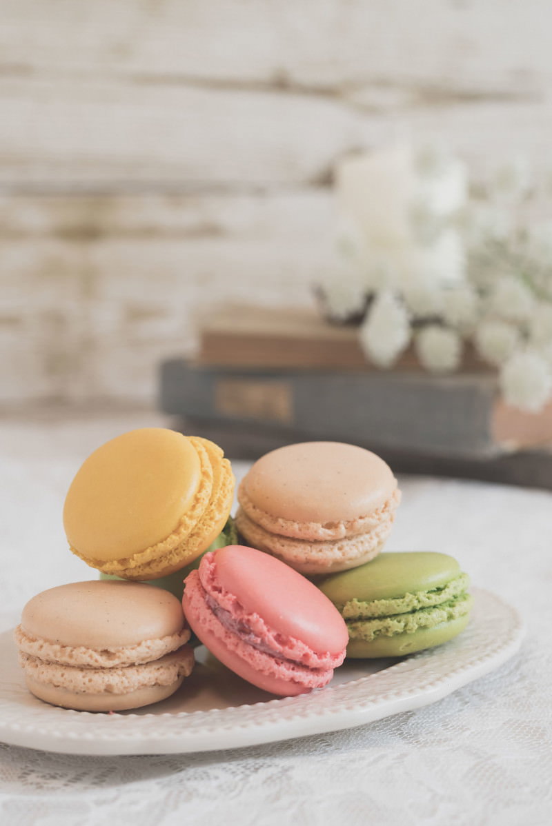 白い皿に盛り付けられたカラフルなマカロンがテーブルに置かれている