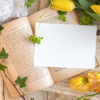 洋書の上に置かれた真っ白なハガキとレモンの写真
