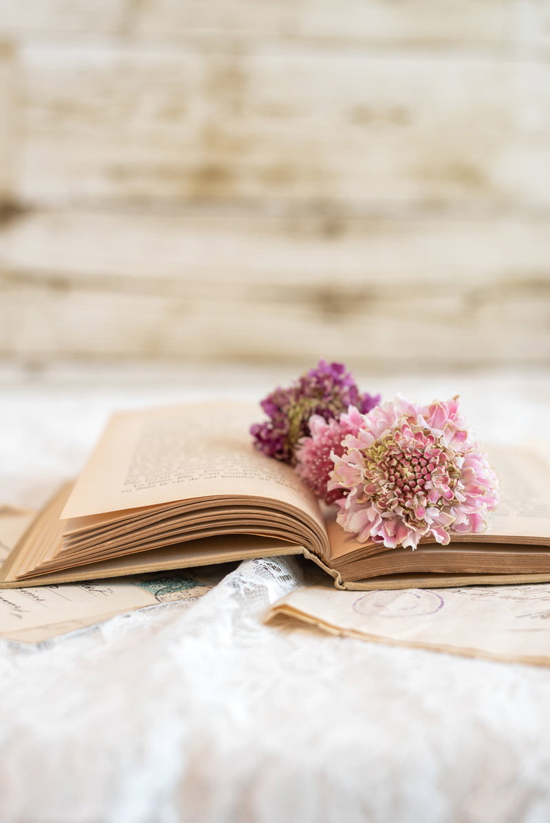 木目のテーブルに置かれた開いた洋書と花のしおり