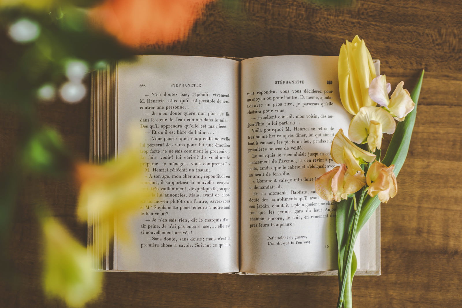 開いた洋書の周りに黄色い水仙の花が置かれている様子