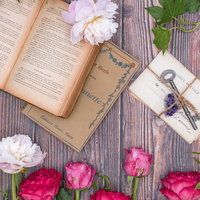 生花のバラに包まれる古書と手紙 ロマンチックなテーブル風景の写真