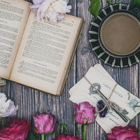 テーブル上に並ぶティーカップ、洋書、鍵、薔薇のアンティーク配置の写真