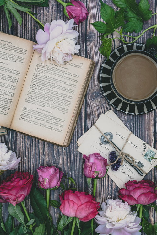 テーブル上に並ぶティーカップ、洋書、鍵、薔薇のアンティーク配置