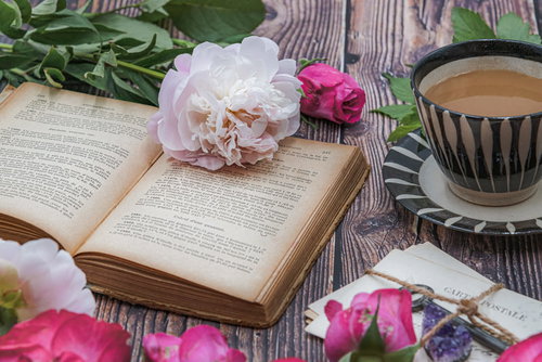 古書と手紙に添えたバラ、ティーカップのある読書時間