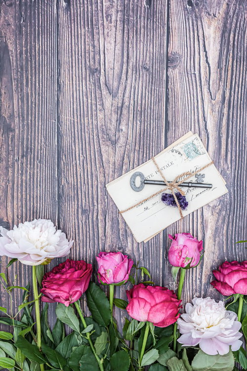 生花の薔薇と芍薬の香りに包まれた、紐で結ばれた手紙と鍵