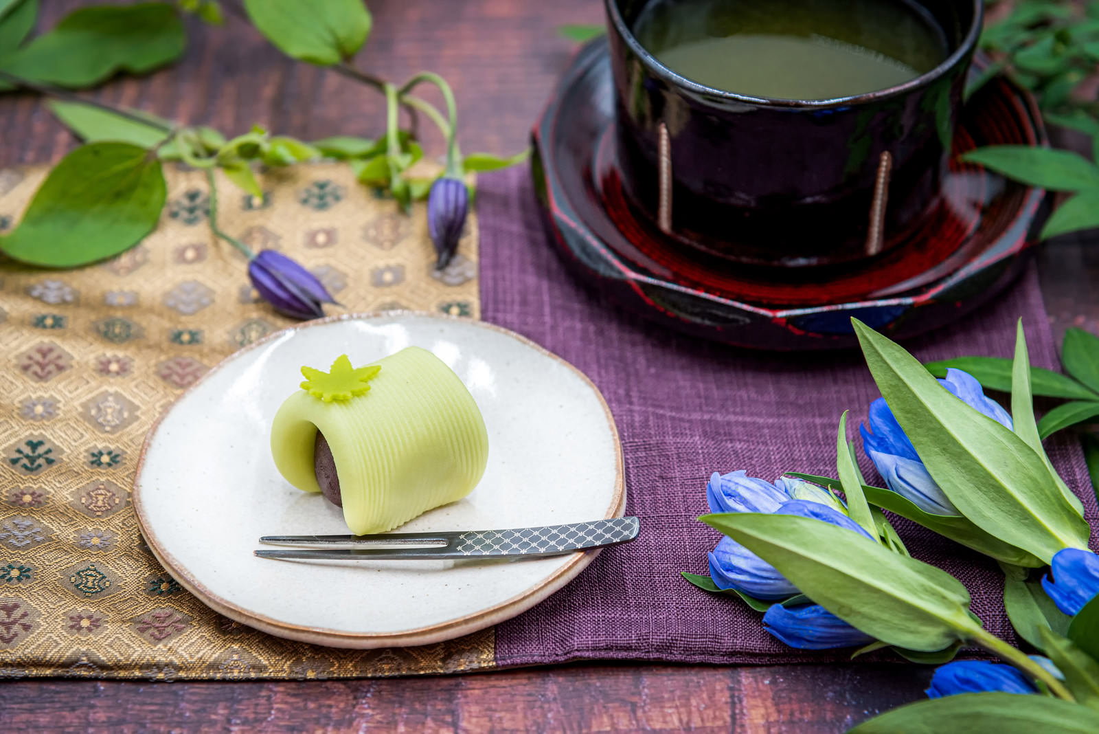 白いお皿に緑色の練り切りとティーカップに入ったお茶