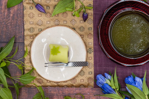 白い皿に盛られた緑色の練り切りと抹茶のお茶を俯瞰で配置