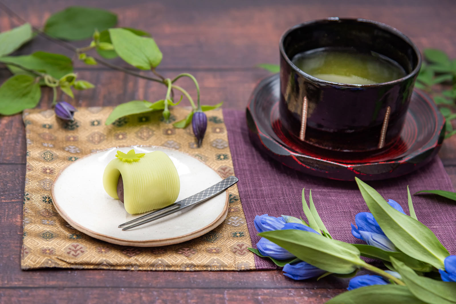 白い皿の練り切りと黒い茶碗の抹茶が木製トレイに並ぶ