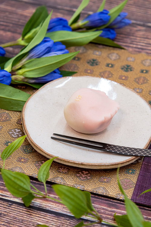 白いお皿に盛られた薄いピンク色の練り切りと黒い楊枝