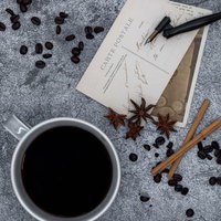 散らばるコーヒー豆と絵葉書、手紙、万年筆のカフェ風スタイリングの写真