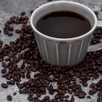 グレーのカップに入ったブラックコーヒーとコーヒー豆で飾る珈琲の写真