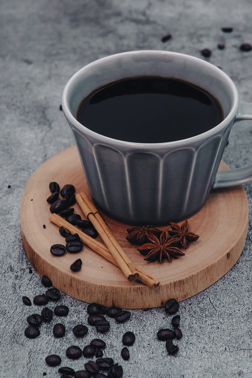 木製コースターに置かれた珈琲とシナモンスティック