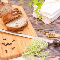 木製カッティングボード上のパン切り包丁とスライスされたパンの写真