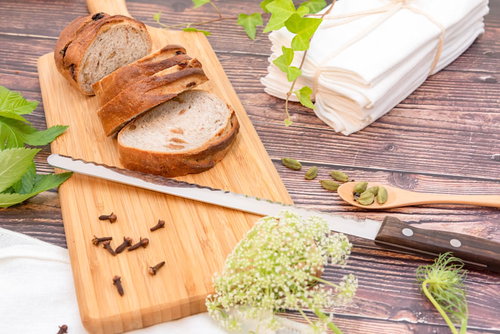 木製カッティングボード上のパン切り包丁とスライスされたパン