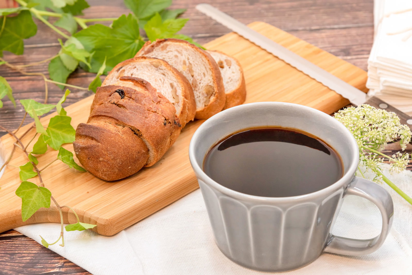木製のまな板にスライスされたパンとグレーのコーヒーカップ