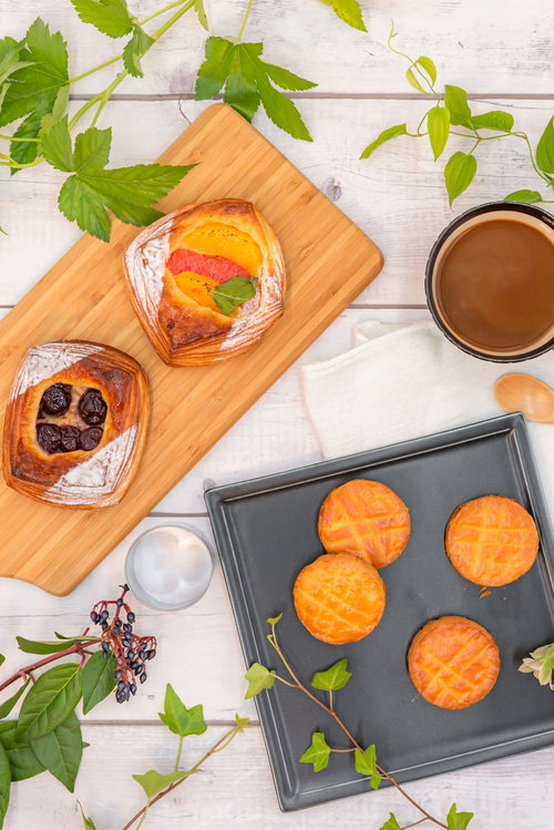 木製カッティングボードに並ぶフルーツデニッシュとガレットブルトンヌを俯瞰撮影