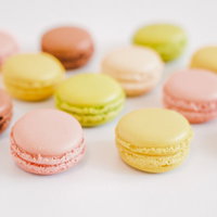 ピンク、イエロー、グリーンなど色とりどりに並べた洋菓子マカロンの写真