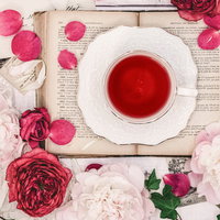 白いカップに入ったローズティーの周りに散らばる薔薇の花弁の写真