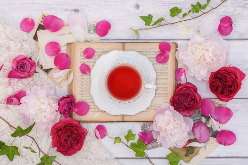 白いテーブルに散らばる薔薇の花びらとローズティー