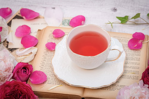 古書に置かれたローズティーと薔薇の花弁のティータイム