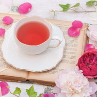 読みかけの洋書に置いたローズティーと薔薇の花弁の写真