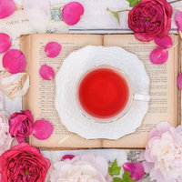 白いカップに注いだローズティーと薔薇の花、花弁で彩った一杯の写真