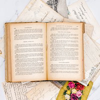 絵はがきの上に置かれた開かれた古書と手紙の写真