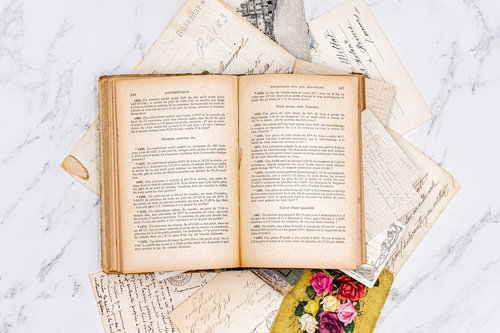 絵はがきの上に置かれた開かれた古書と手紙