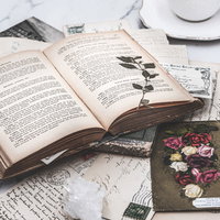 古びた洋書と絵はがき、コーヒーのある静物の写真